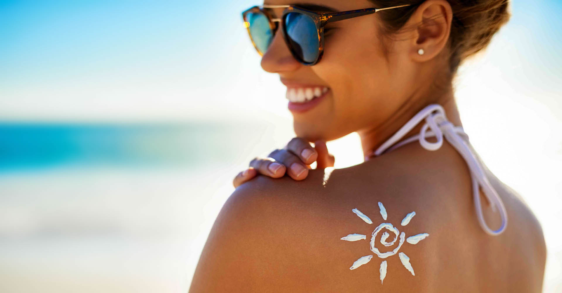 immagine di una ragazza, in spiaggia, presa di lato che sorride